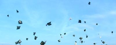 Graduation caps thrown into a blue sky.